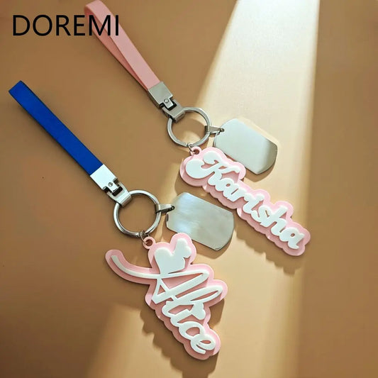 Keychain with pink and blue straps and 'Doremi' branding on a beige background