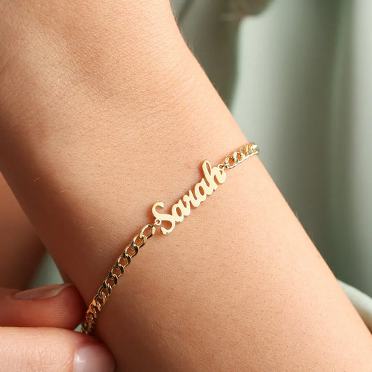 Gold bracelet with 'Sara' on a wrist against a neutral background