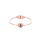 A rose gold bangle bracelet with a central compass design featuring a dark brown gemstone and a small clear accent stone, shown on a plain white background.