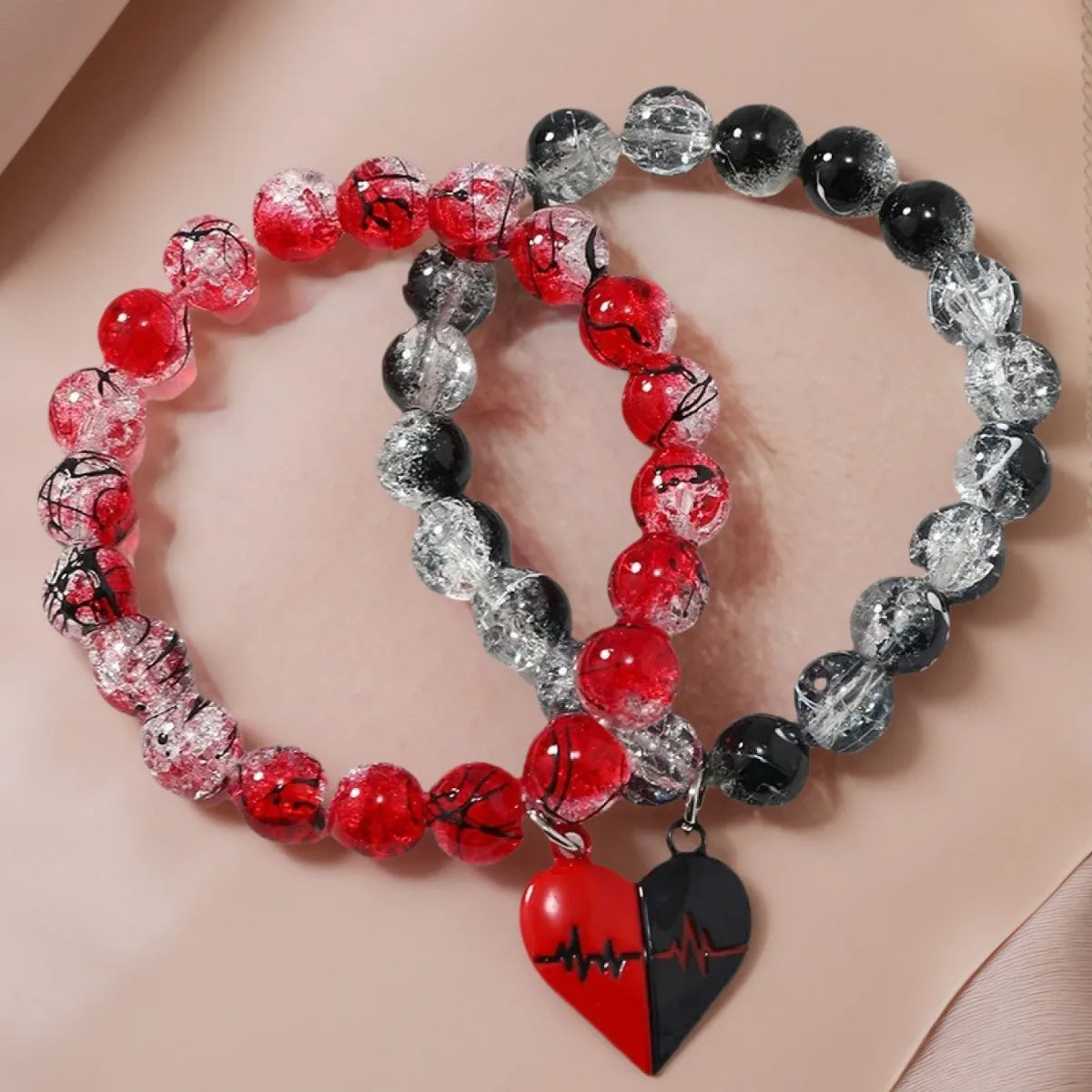 Two beaded bracelets with heart-shaped charms on a beige background