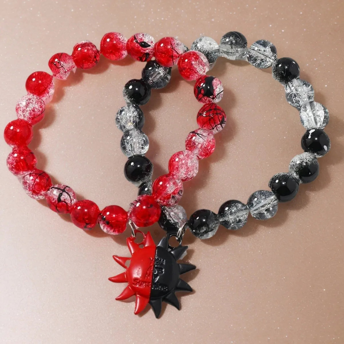 Two beaded bracelets with red, black, and clear beads on a beige background