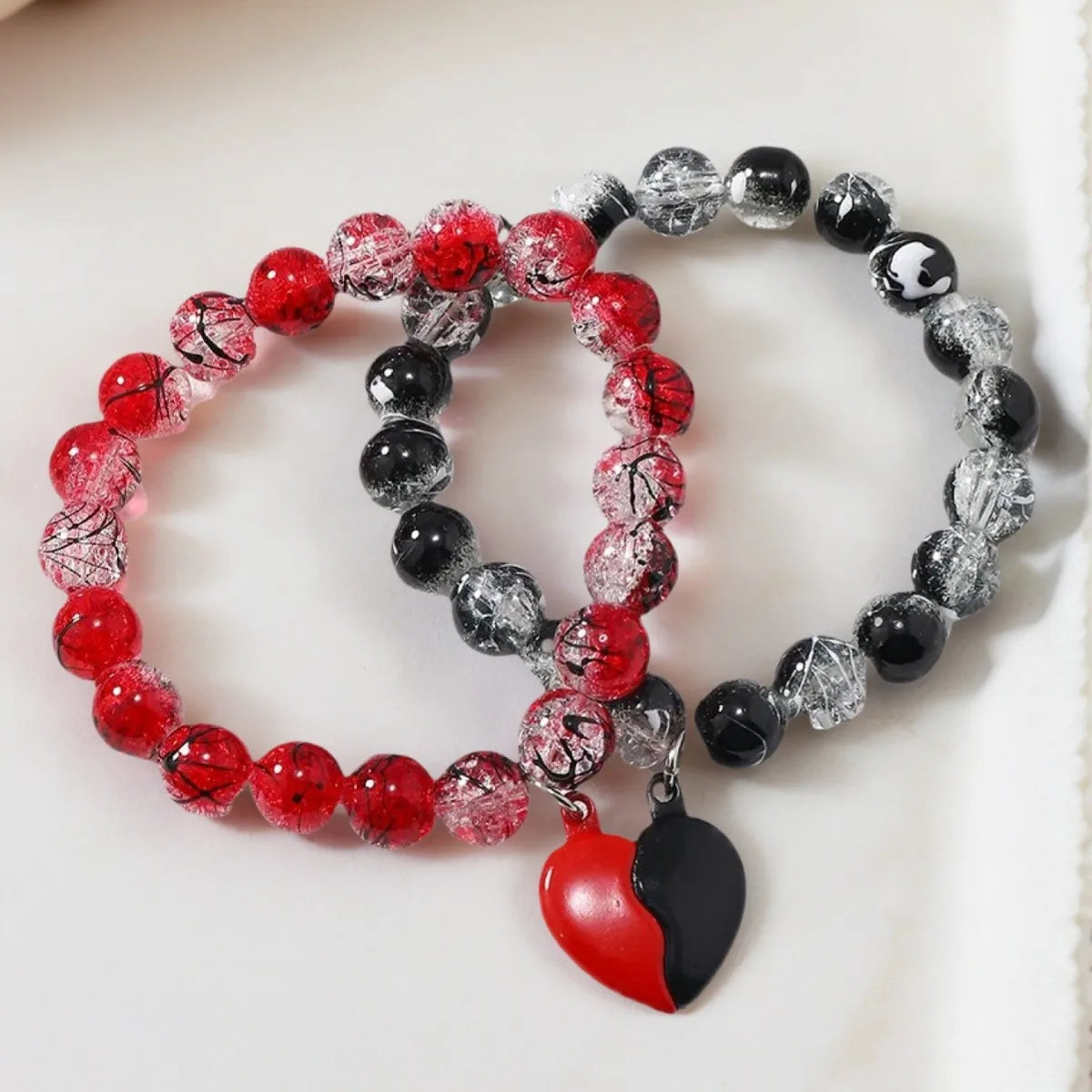 Two beaded bracelets with a heart charm on a white background