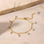 Gold bracelet with pearls on a beige stone surface