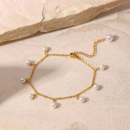 Gold bracelet with pearls on a beige stone surface