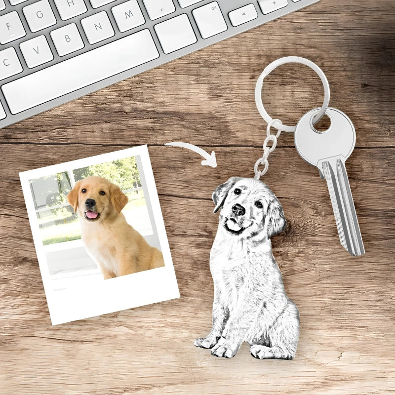 A silver metal keychain shaped like a sitting dog with a key attached, displayed on a wooden surface next to a printed photo of a golden retriever and an arrow pointing to the dog keychain. A partial keyboard is visible at the top.