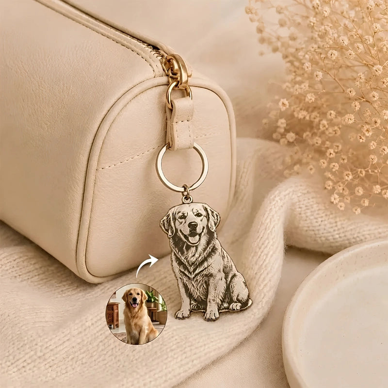 A cream-colored leather zippered pouch with a gold-tone zipper, featuring a custom engraved metal keychain charm shaped like a sitting golden retriever dog. The charm includes a small circular inset showing the reference photo of the dog used for the engraving.