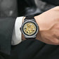 Luxury watch with black and gold design on a person's wrist, wearing a suit.