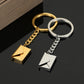Gold and silver keychains with envelope charms on a dark surface