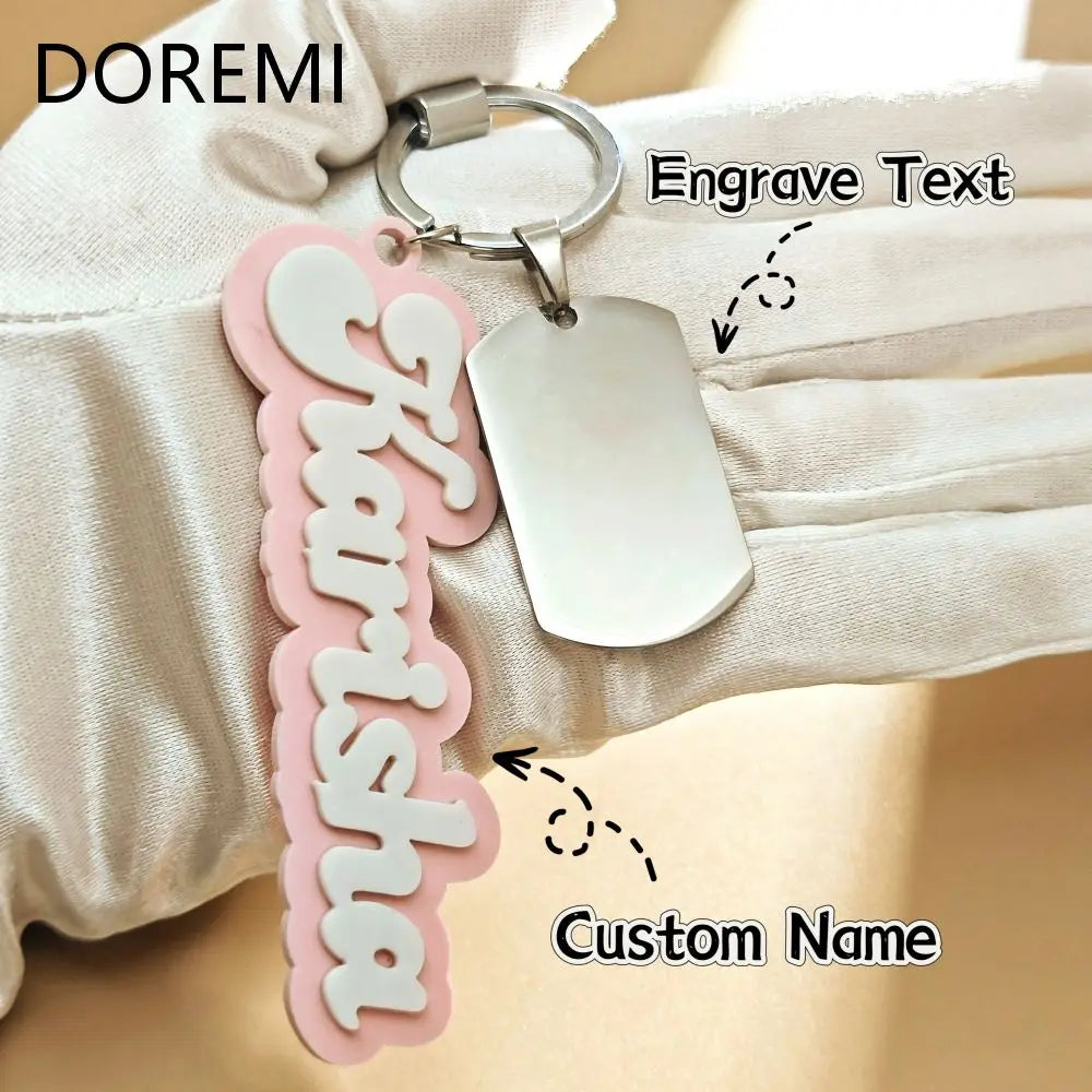 Pink keychain with engraved name 'Shamisha' and a silver tag on a beige fabric background.