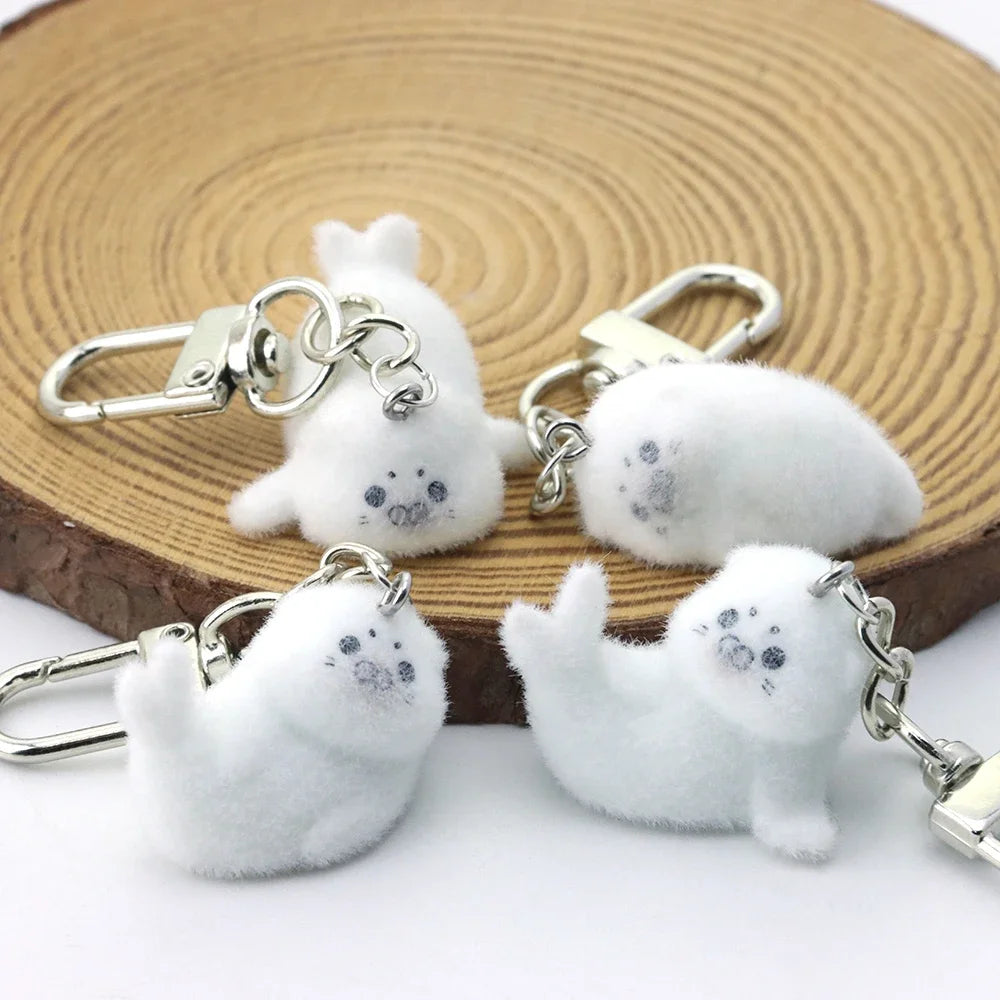 Four white fluffy keychains shaped like dogs on a wooden surface.