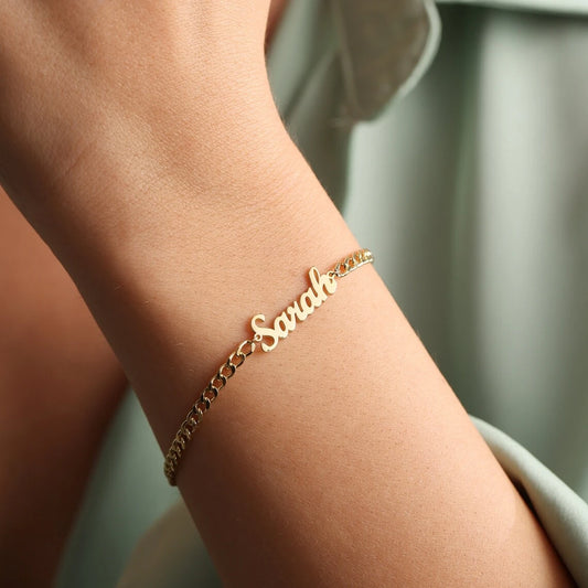 Gold bracelet with 'Sasha' on a wrist against a neutral background