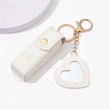 White heart-shaped keychain with gold accents on a light gray background