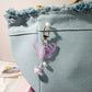 Butterfly-shaped keychain attached to a denim bag with a blurred background