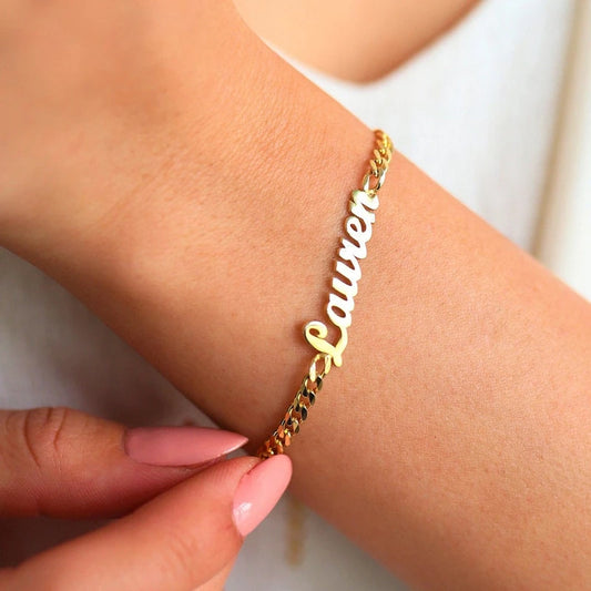 Gold bracelet with 'Lauren' on a wrist against a white background