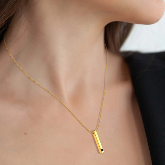 Gold necklace with a vertical bar pendant on a person's neck