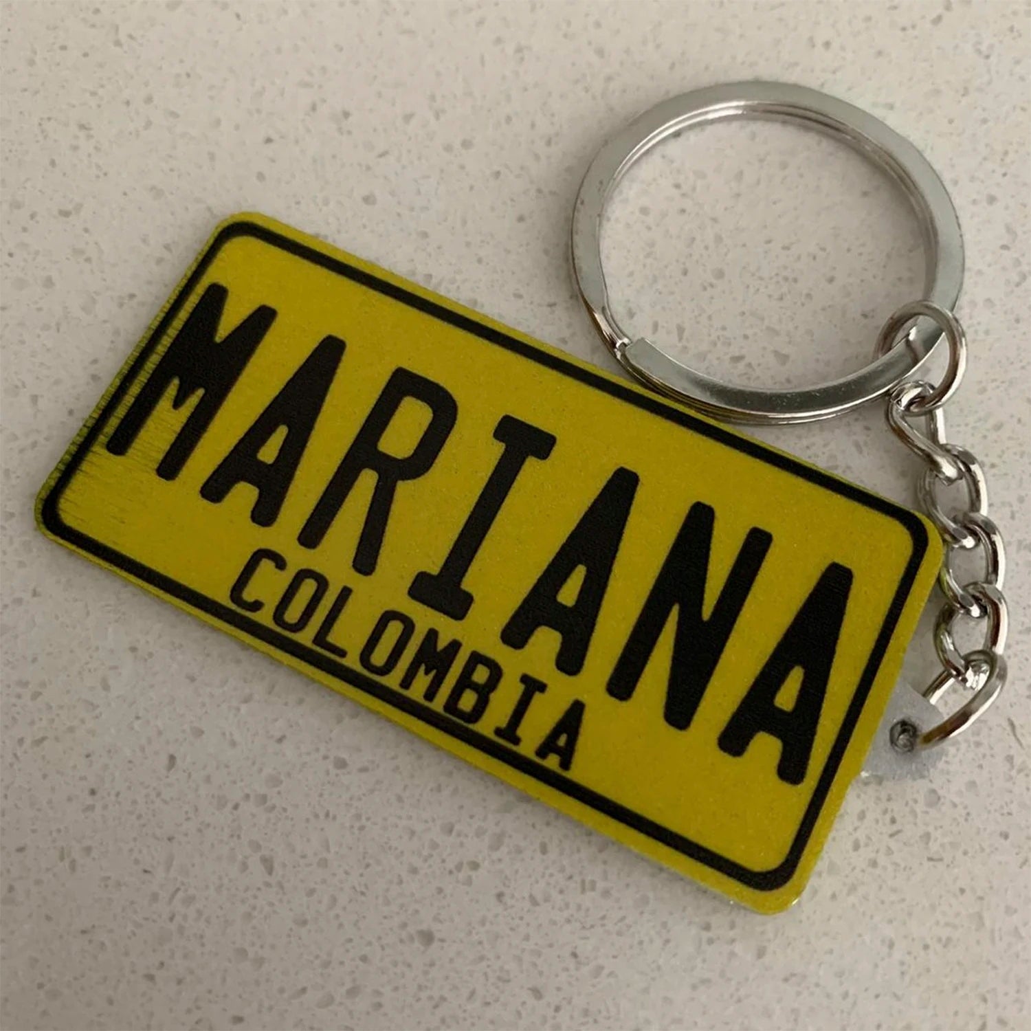 Yellow keychain with 'MARIANA COLOMBIA' text on a gray surface