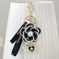 Decorative keychain with black flower design, pearl embellishments, and heart charm on a white background.