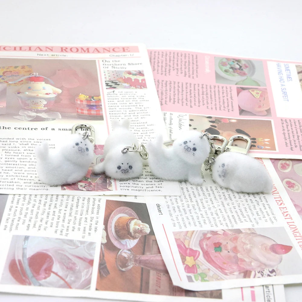 White plush keychains shaped like seals on a newspaper background
