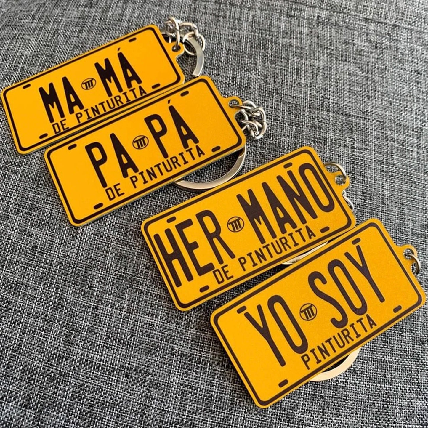Yellow license plate keychains with black text on a gray textured background