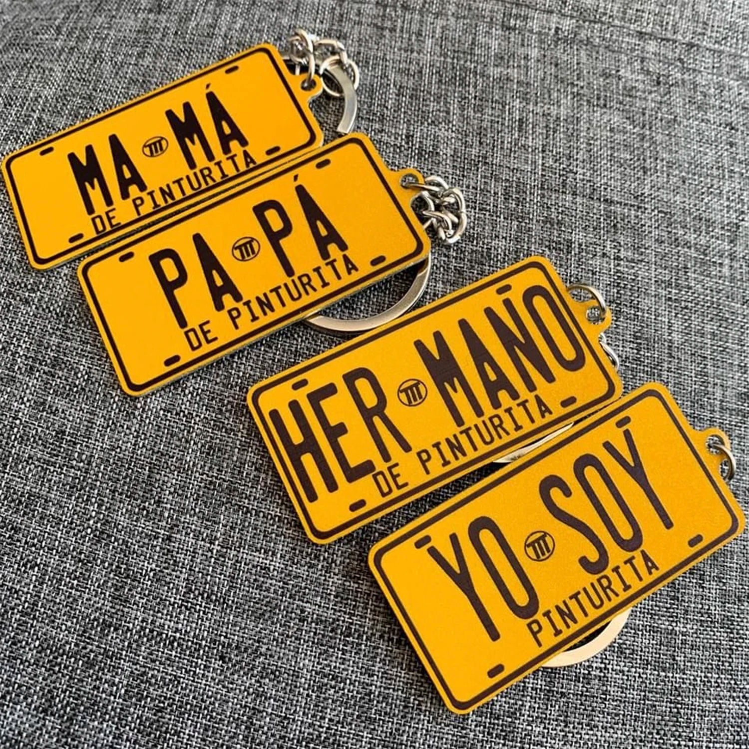 Yellow license plate keychains with black text on a gray textured background