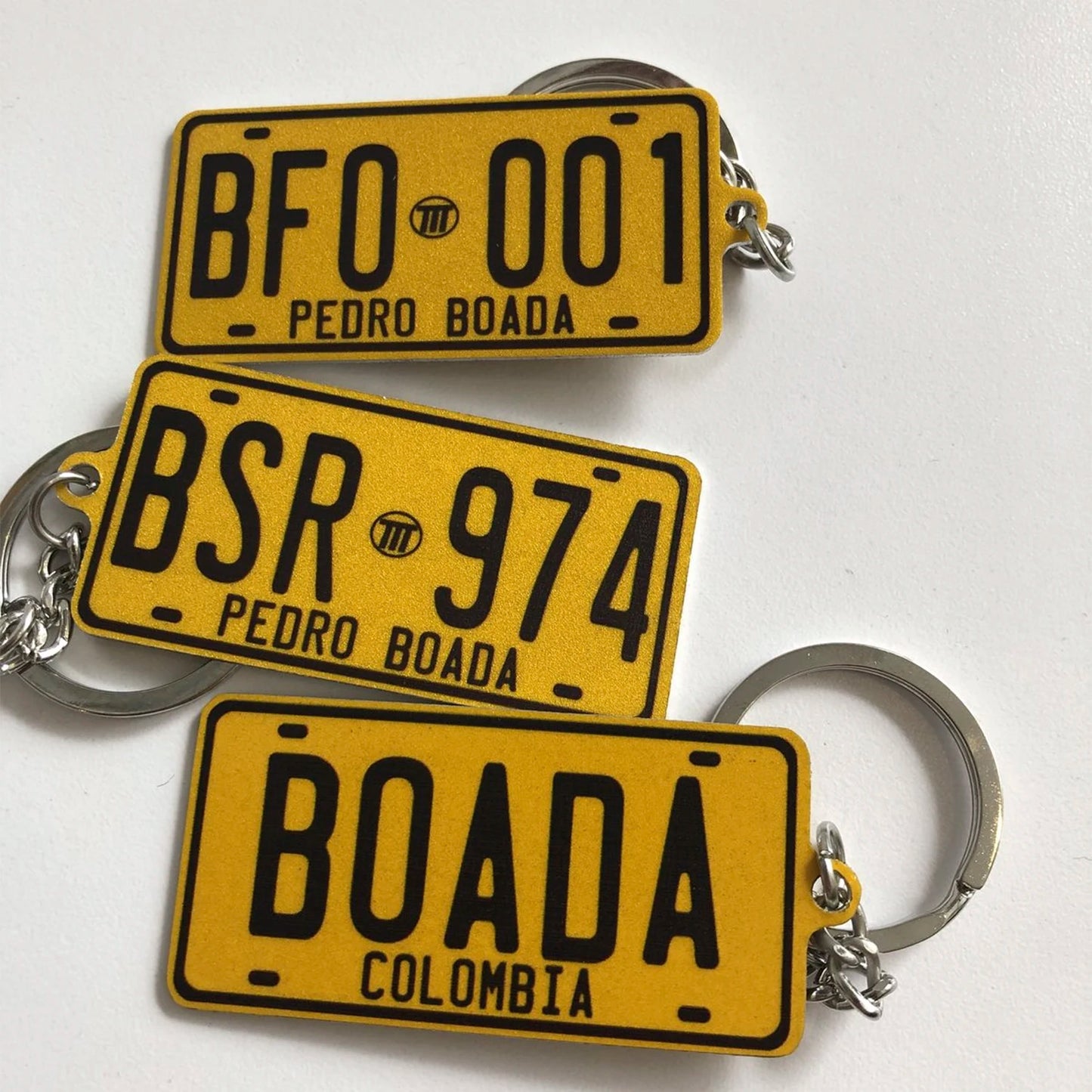 Three yellow license plate keychains with black text on a white background