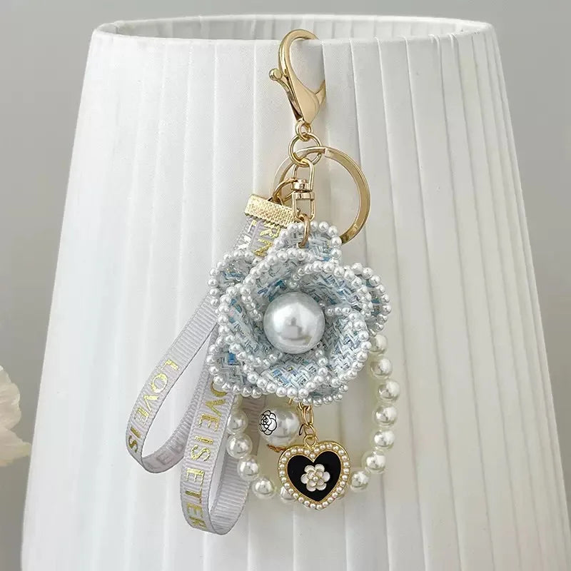 Decorative keychain with flowers and pearls on a white background