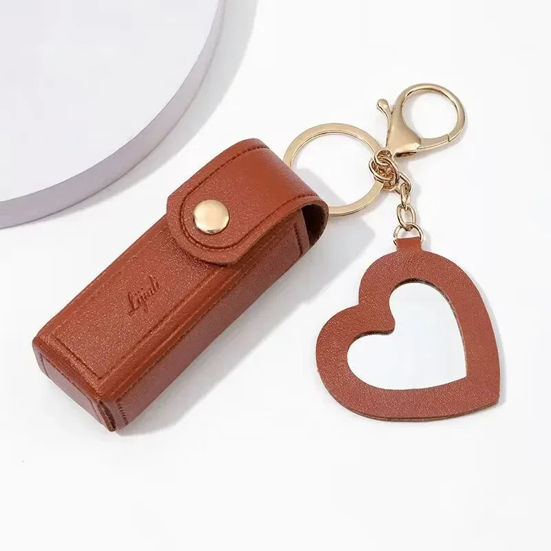 Brown leather key case with gold clasp and heart-shaped keychain on a white background