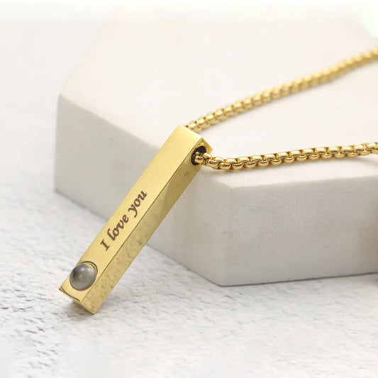 Gold necklace with 'I love you' pendant on a white surface