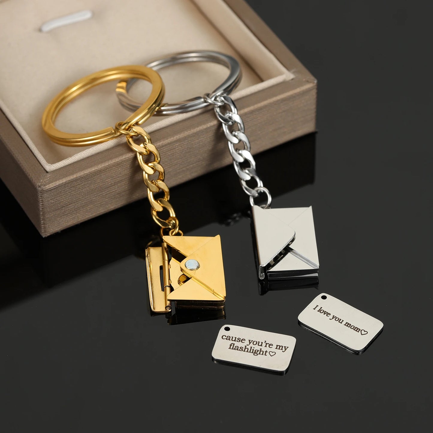 Gold and silver keychains with attached charms on a dark surface.