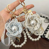 Pearl and beaded keychains held by a hand with a blurred background
